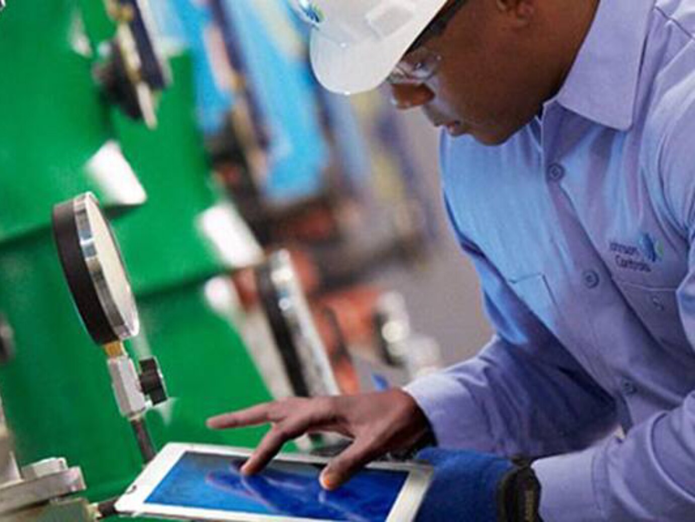 A construction worker in a hat operates a tablet computer, engaged in his task