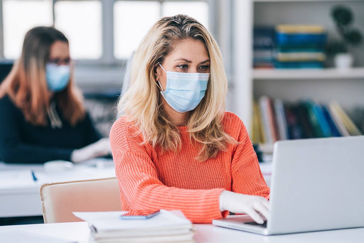 Woman wearing PPE in university classroom.